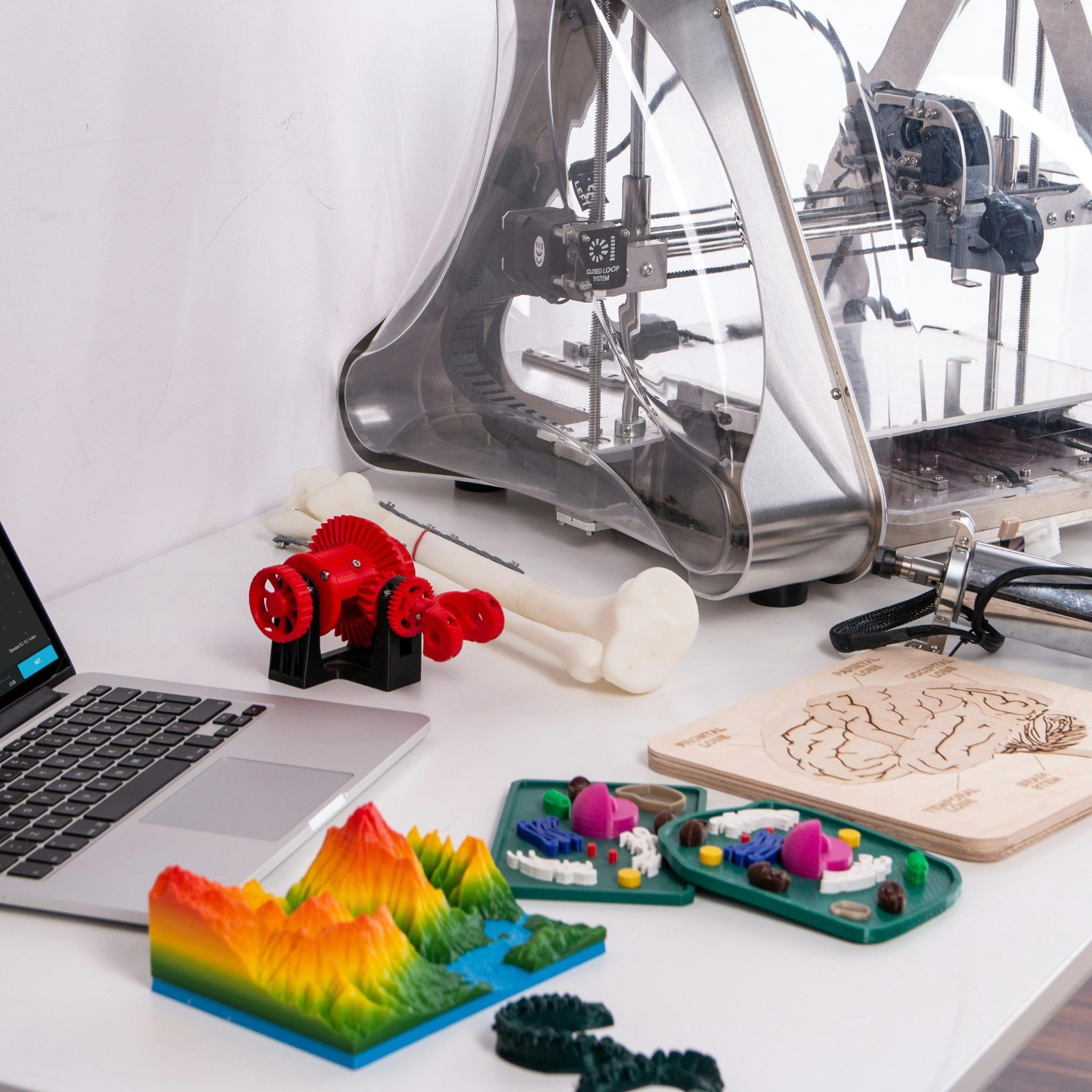Bild zeigt einen 3D-Drucker, einen Laptop und andere technische Geräte