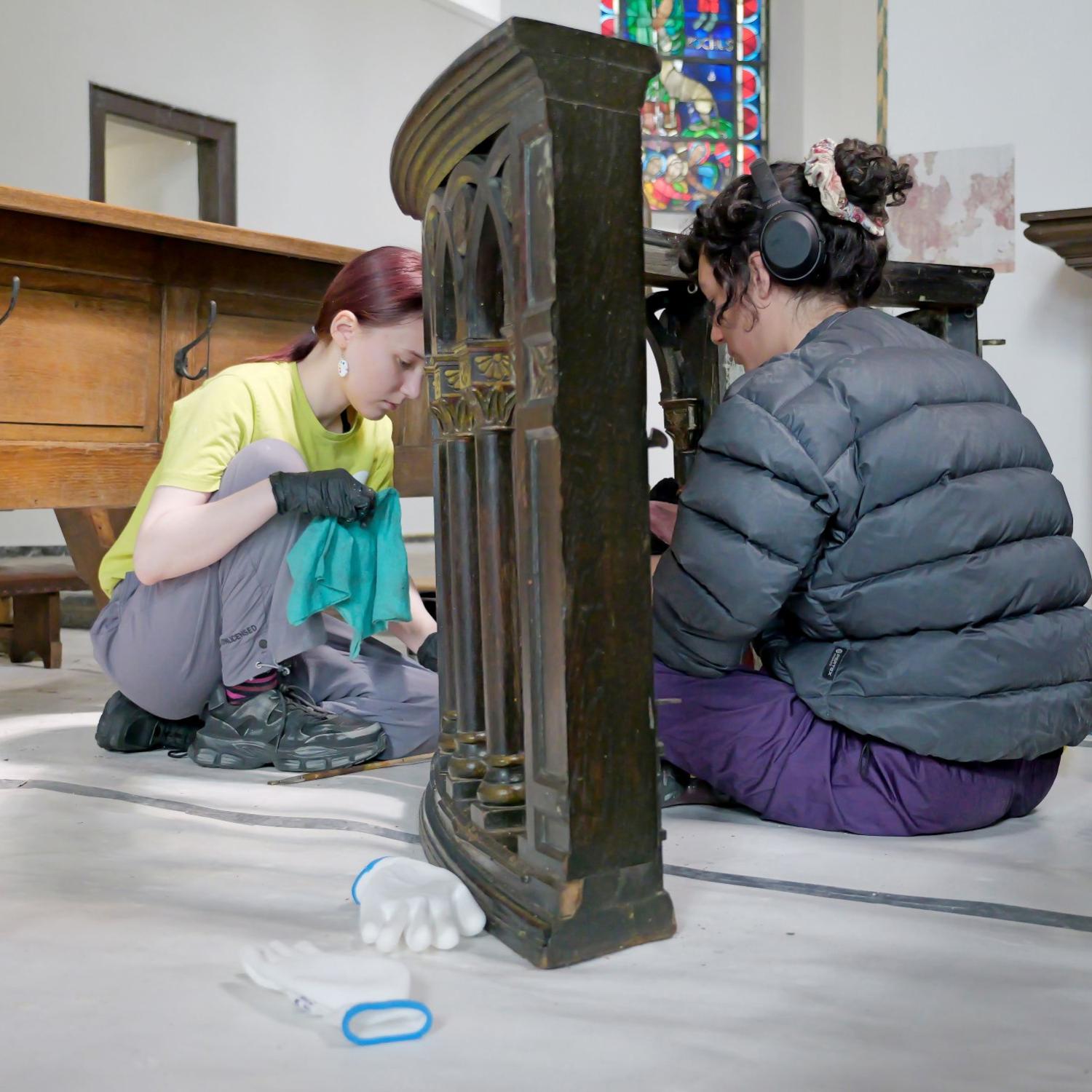 Mit Feingefühl: Elianne (li.) und Elena entfernen den Schlamm von einer alten Kirchenbank.