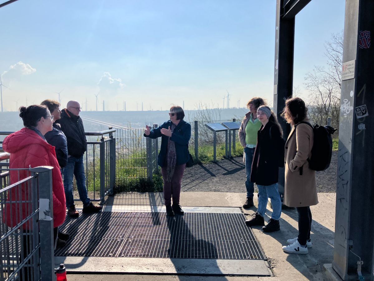 Menschen stehen auf einem Aussichtspunkt beim Braunkohletagebau.