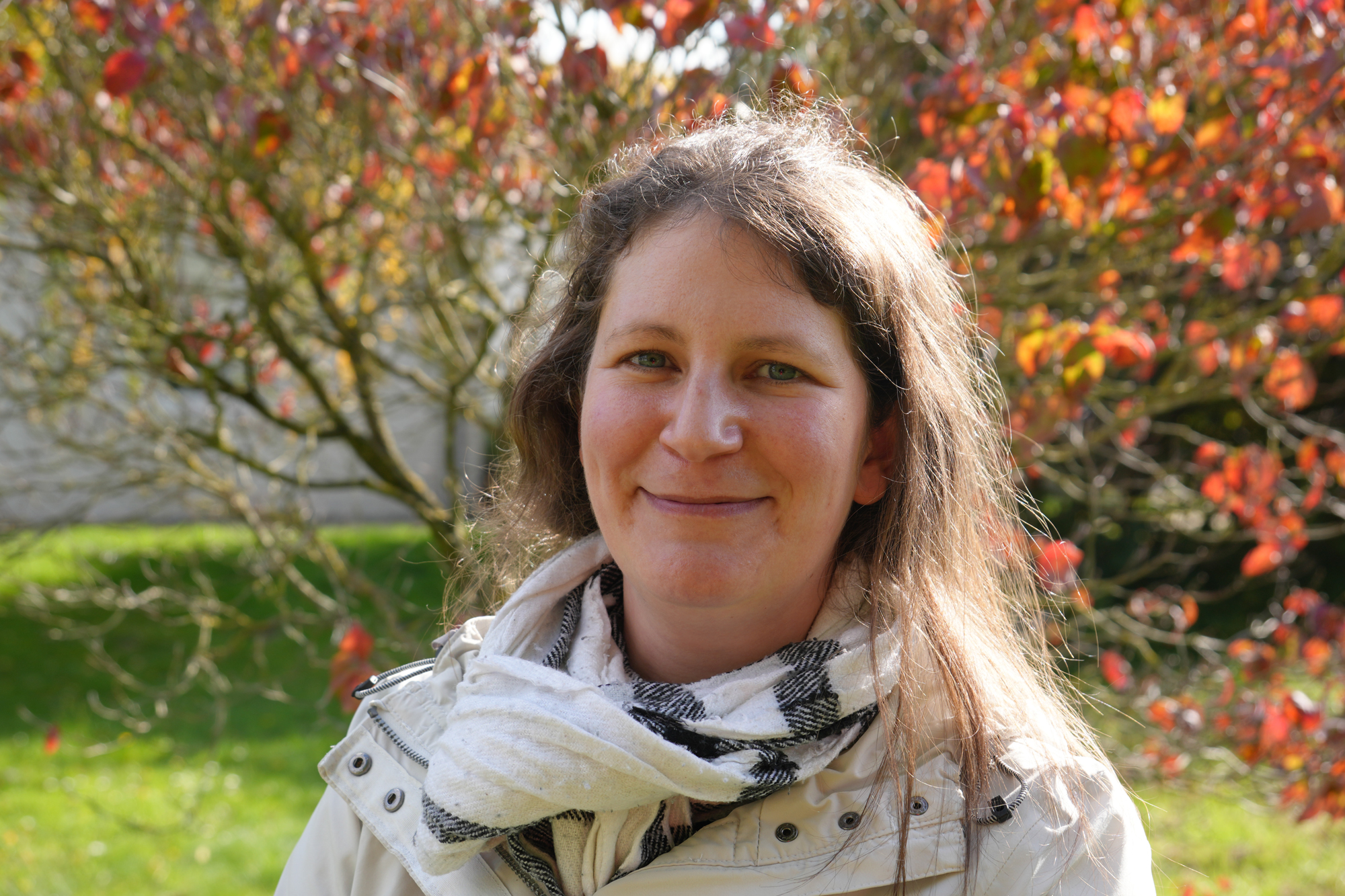 Eine Frau vor einem herbstlich gefärbtem Baum.