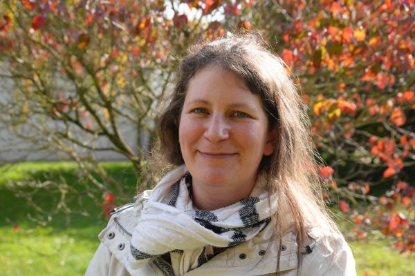 Eine Frau vor einem herbstlich gefärbtem Baum.