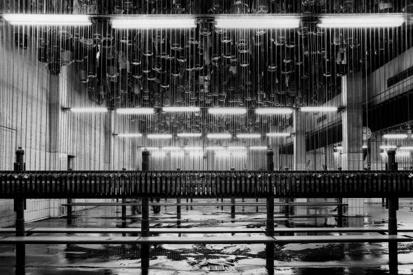 Eine Halle mit nassem Boden und aufgehängten Eimern an der Decke, dazwischen Sitzbänke.