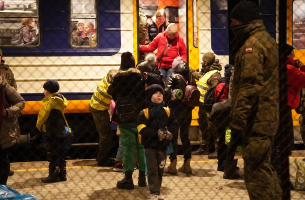 Kinder steigen aus einem Zug. Ein Kind schaut einen Soldaten an.